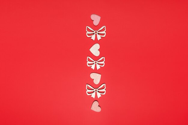 Flat lay of hearts and bow in line on red bright background.