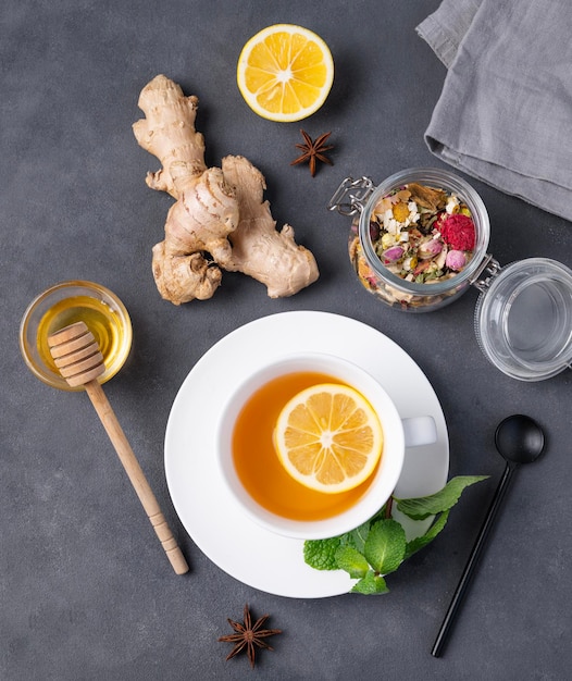 Flat lay herbal cup of tea with lemon honey and mint on a dark background The concept of a healthy drink for immunity with ginger and spicy