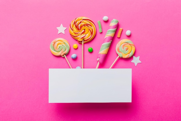 Photo flat lay holiday composition paper blank lollipop birthday decorations on colored background top view copy space for text