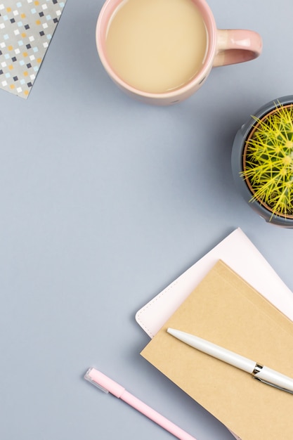 Flat lay home office desk. Female workspace with note book, eyeglasses, tea mug, diary, plant. Copy space