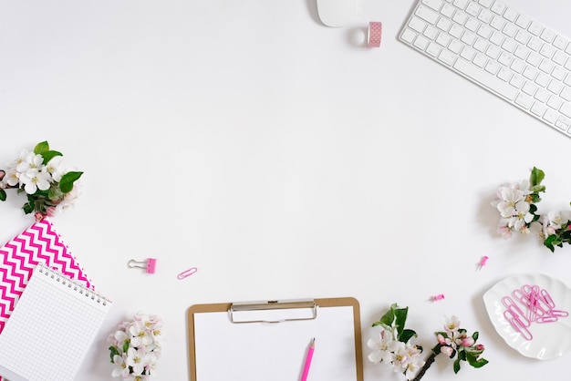 Flat lay home office workspace female blogger background with white modern keyboard notebook and apple flowers copy space on white background