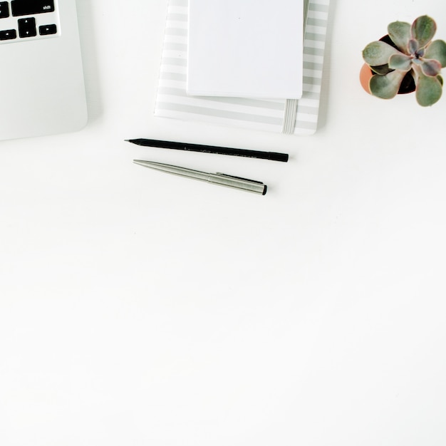 Flat lay home office workspace with laptop, diary, succulent and headphones, on white