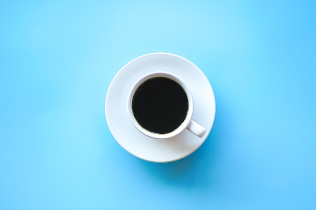 Flat lay of hot americano coffee in white coffee cup on blue background Minimal style concept