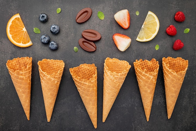 Flat lay ice cream cones collection on dark stone background . Blank crispy ice cream cone with copy space for sweets menu design.