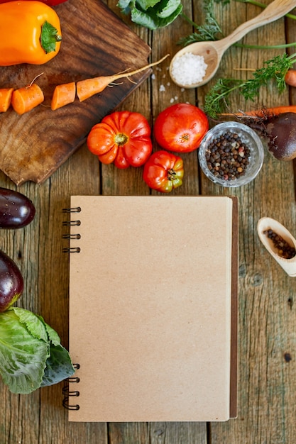 Foto disposizione piatta dell'ingrediente di cucina, verdure intorno al ricettario, drogheria, cibo locale, alimentazione sana e pulita, cibo vegetariano e vegano, concetto di primavera dietetica, vista dall'alto, spazio copia.