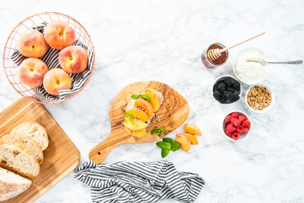 Flat lay. Ingredients for preparing peach ricotta toast on a marble countertop.