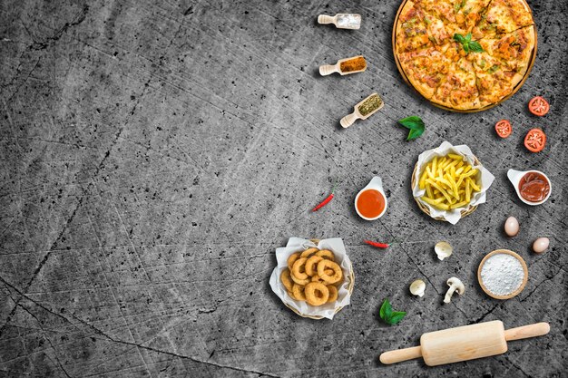 Foto flat lay italiaanse pizza en ingrediënt frietjes en knapperige ui ringen met saus