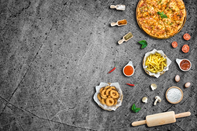 Photo flat lay italian pizza and ingredient french fries and crispy onion rings with sauce