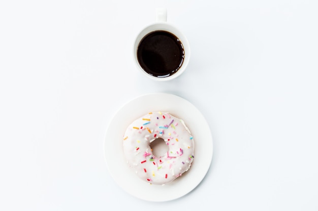Flat lay items: coffee cup and donut lying on white background