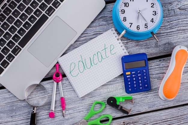 Flat lay items for studying and educating. Laptop pc with calculator scissors and stapler on white wooden table.