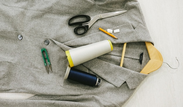 Photo flat lay. on the jacket lie scissors, a pencil, color spools, chalk, scissors for yarn, a hanger.