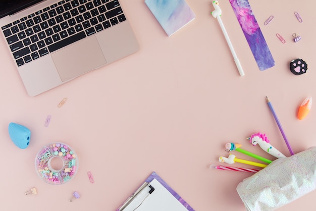 Flat lay of kawaii stylish school stationery and laptop on pink. 