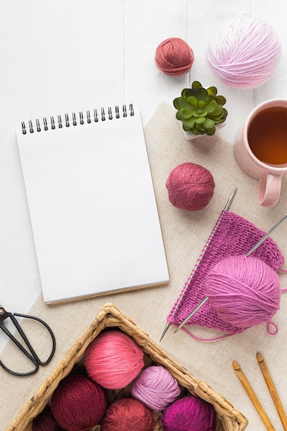 flat lay of knitting set with notebook and  yarn