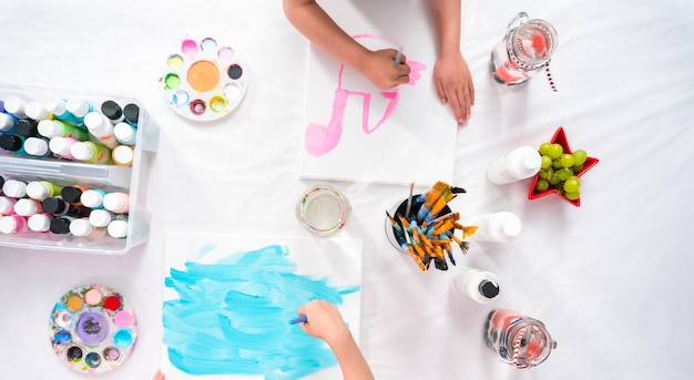 Photo flat lay. little girls are painting on canvas with acrylic paint.