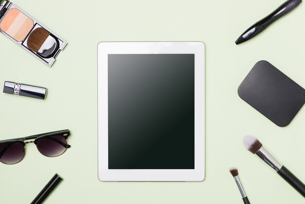 밝은 색 배경에 디지털 태블릿이 있는 메이크업 화장품의 평평한 위치
