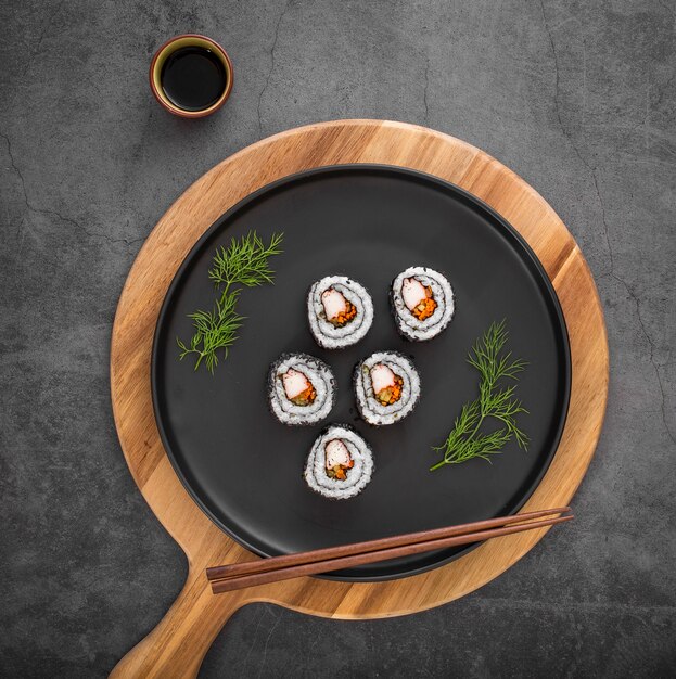 Flat lay maki sushi rolls with chopsticks and soy sauce