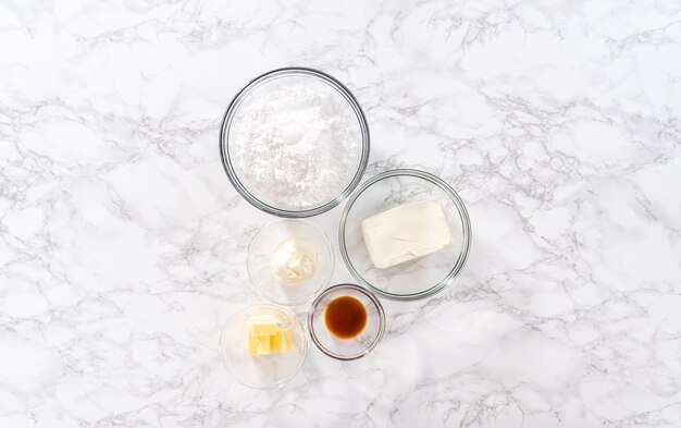 Photo flat lay. measured ingredients in a glass mixing bowl to prepare cream cheese frosting.