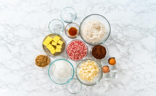 Flat lay. Measured ingredients in a glass mixing bowl to prepare peppermint white chocolate cookies.