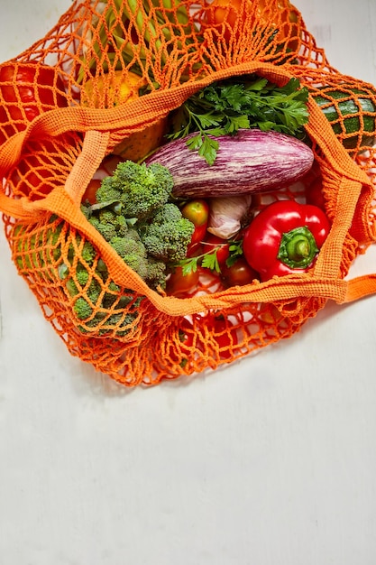 Flat lay mesh grocery shopping eco friendly bag with vegetable and greens, zero waste cconcept, local farmers market, shopping mall, top view, copy space, plastic free items.