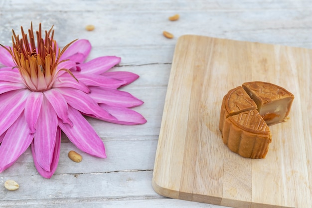 Flat lay of Mid Autumn festival Moon cake on old white table with pink water lily.