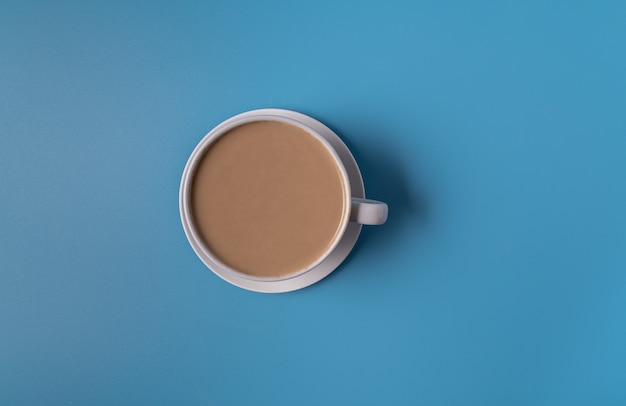 Photo flat lay milk coffee in a white cup on blue