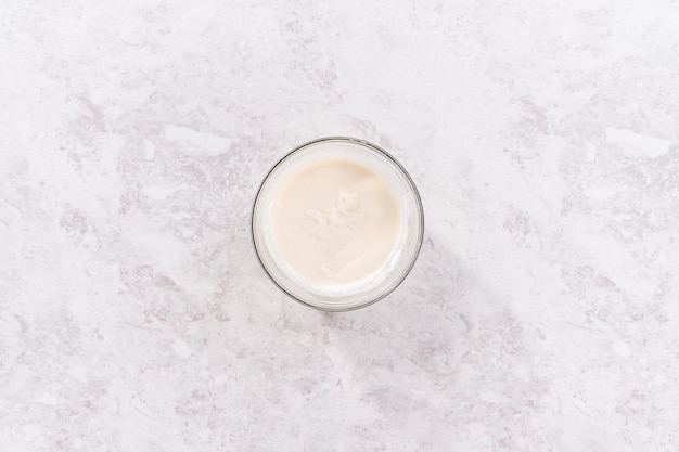 Photo flat lay. mixing ingredients in a glass mixing bowl to prepare cream cheese frosting.