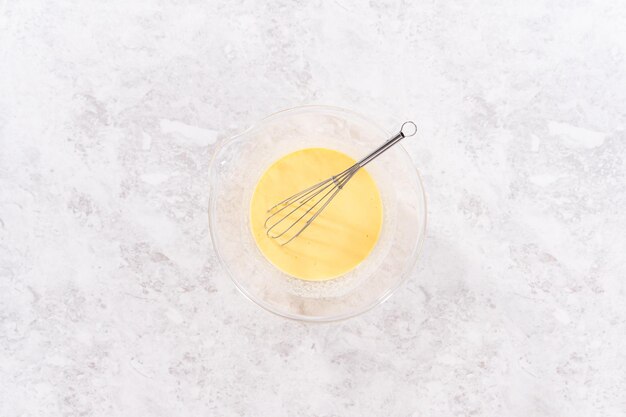 Flat lay. Mixing ingredients in a glass mixing bowl to prepare red velvet bundt cake.