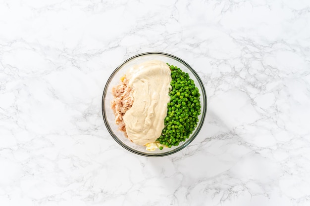 Flat lay Mixing ingredients in a large glass mixing bowl to make macaroni salad with chicken