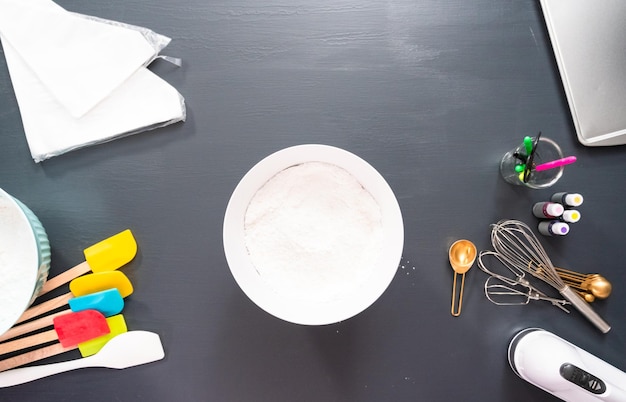 Flat lay. Mixing royal icing of different colors to decorate sugar cookies.