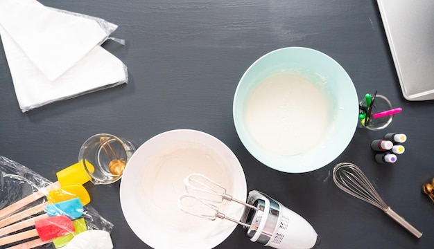 Flat lay. Mixing royal icing of different colors to decorate sugar cookies.