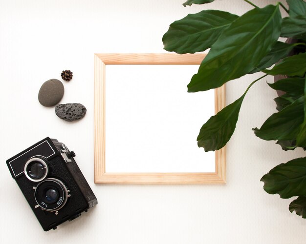 Flat lay mock up, top view, wooden frame, old camera, plant and stones.