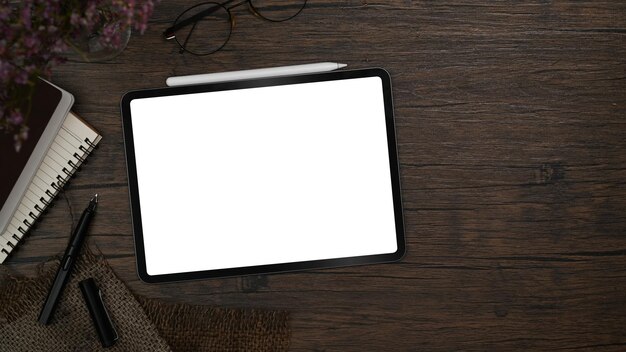 Photo flat lay mockup digital tablet with empty display stylus pen and notebook on wooden table