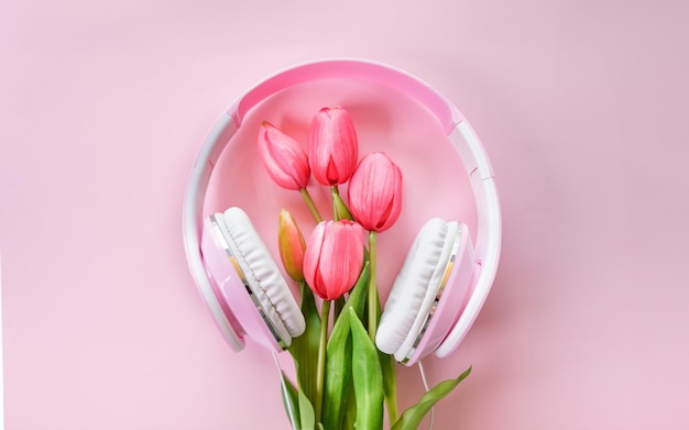 Flat lay mockup with headphones and tulips and petals Pink background