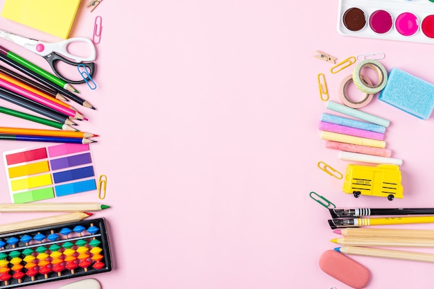 Flat lay of modern pink office desktop with school supplies