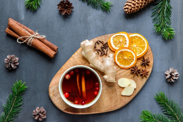 Flat lay of mug of hot tea with lemon, cranberries, cloves, anise, ginger