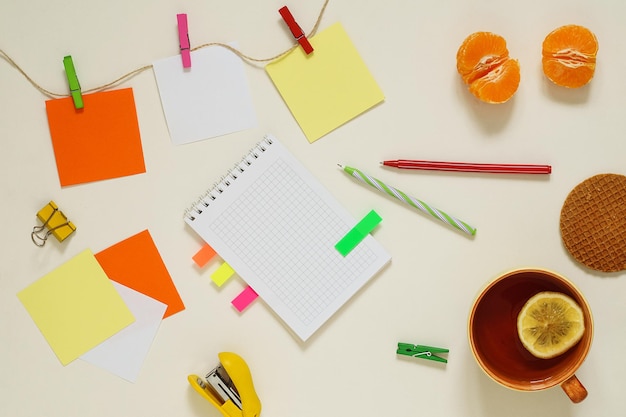 Photo flat lay of multicolored paper stickers with clothespins, tea and stationery. copy space