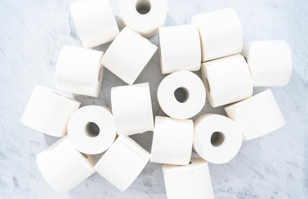 Flat lay. New white toilet paper rolls on a gray background.