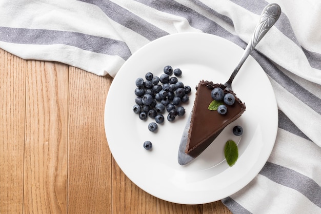 Фото Плоский кусок шоколадного торта на тарелке с черникой