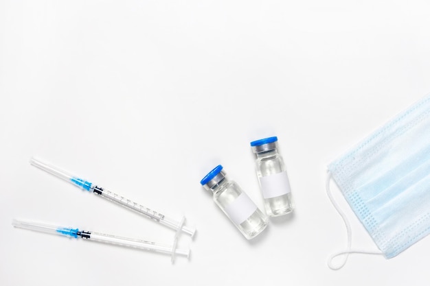 흰색에 인플루엔자 백신용 주사기 보호용 또는 의료용 마스크와 병의 평평한 위치