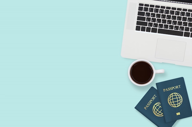 Фото Плоская планировка с двумя паспортами, кофейной чашкой и компьютерным ноутбуком пастельного синего цвета с copyspace