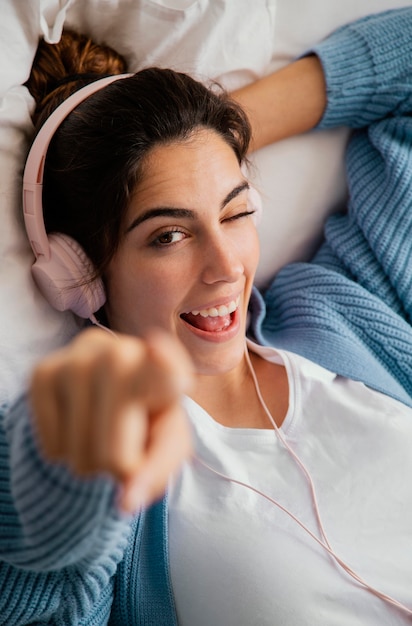 Фото Плоская планировка молодой женщины, слушающей музыку в наушниках и указывающей
