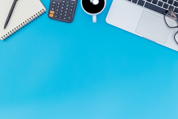 Flat lay office desk table of modern workplace with laptop on blue table, top view laptop background and copy space on black background, blue desk office with laptop