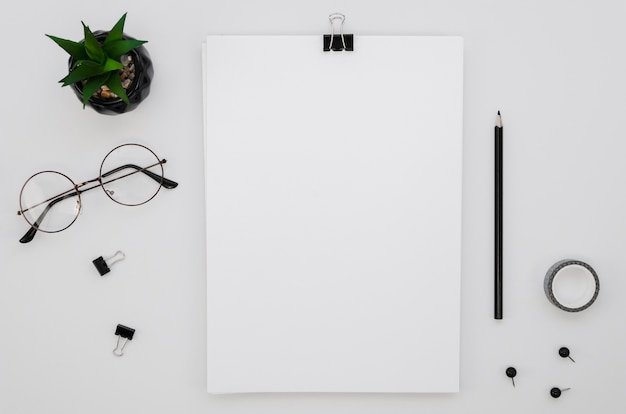 Flat lay of office supplies with glasses and plant