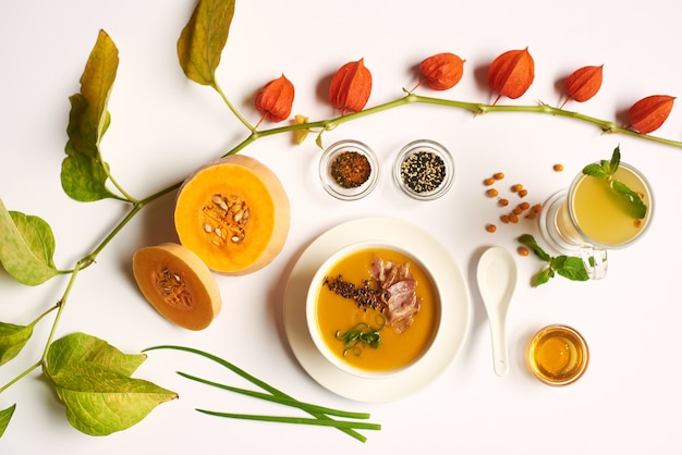 Flat lay of orange cream soup with meat and physalis.