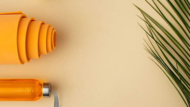 Flat lay orange water bottle and mat