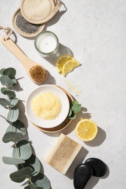 Flat lay organic yellow sea salt with lemon soap massage stone brush sponge and eucalyptus branch on a white textured background The concept of spa and wellness Top view and copy space