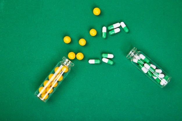 Photo flat lay overhead of yellow and green pills in glass jar on paper background