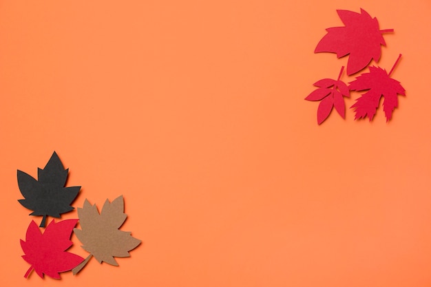 Flat lay paper autumn leaves arrangement on orange background with copy space