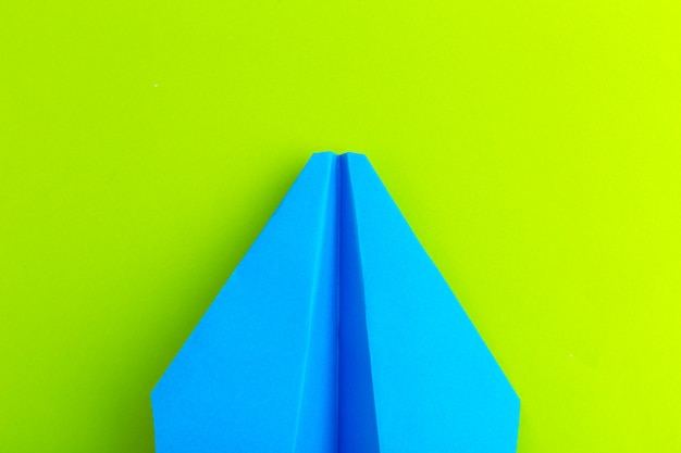 Flat lay of a paper plane on green pastel color background