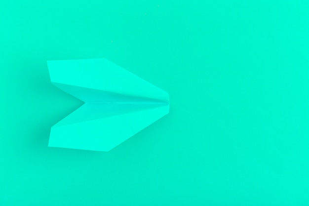 Flat lay of a paper plane on green pastel 